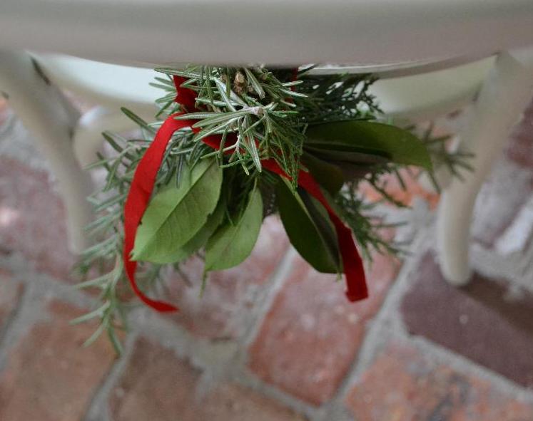 Cottage Fix - fresh greenery chair swag secured with a red velvet ribbon